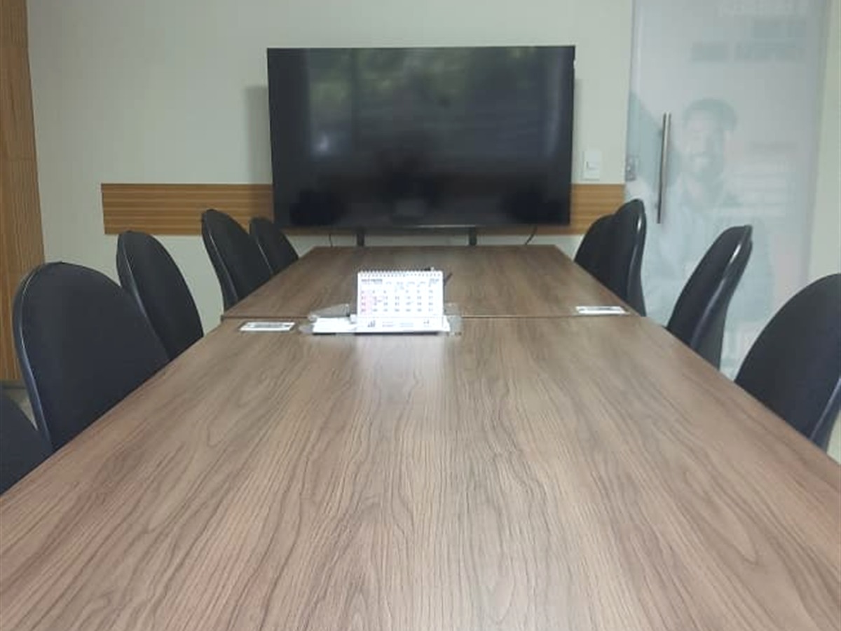 Mesa executiva com cadeiras confortáveis e vista frontal da TV